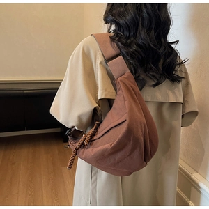 Detail of caramel nylon croissant bag with woven zipper pull and adjustable strap