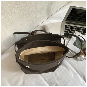 Top view of deep brown large capacity tote bag with beige lining and metal snap closure