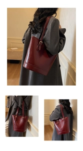 Detail of dark red retro leather bucket tote bag with gold metal hardware on strap