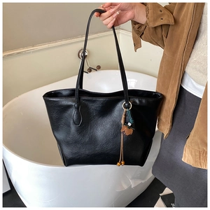 Close-up of black PU tote bag with wrinkled texture and floral pendant detail