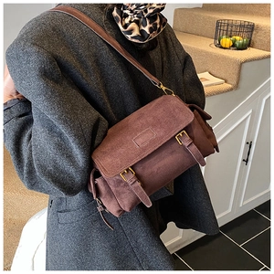 Detailed close-up of a vintage brown faux suede crossbody bag with adjustable strap