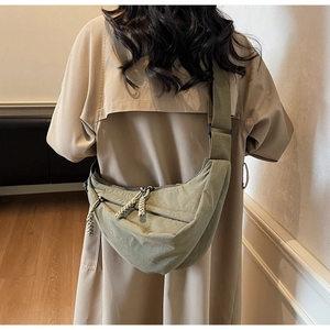 Detailed back view of an olive green nylon crescent bag on a khaki trench coat model
