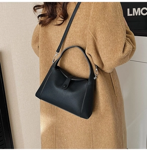 Detail of black lychee grain leather handbag with adjustable strap shown on model