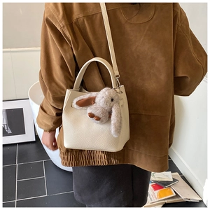Detail of cream white leather bucket bag with lychee texture and plush bunny charm