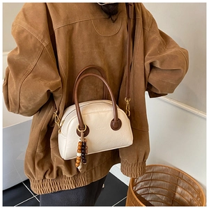 Détail du sac bowling blanc crème avec poignées marron foncé et breloque en bois