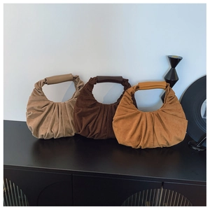 Detailed view of three vintage pleated suede crescent bags in beige, brown, and caramel
