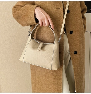 Detail of beige pebbled leather texture and top handle on casual crossbody bag