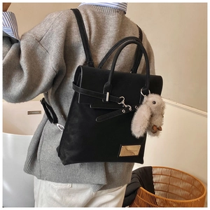 Detail of black leather backpack with decorative silver buckles and cute plush rabbit charm