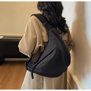 Close-up of black oversized crossbody dumpling bag with wide strap on a model