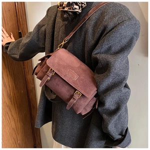 Close-up of deep brown suede messenger bag worn with a wool coat and leopard scarf