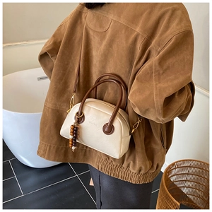 Detailed view of a vintage cream Boston bag with dark brown handles and a stylish wooden bead