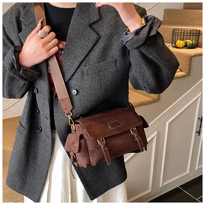 Detail of dark brown faux suede messenger bag with gold buckles and adjustable strap