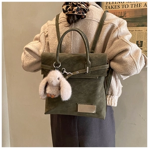 Detailed shot of dark green matte leather backpack with bunny charm and metal buckle