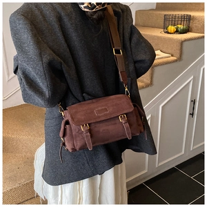 Detail of dark brown faux suede crossbody bag with vintage double buckles and strap