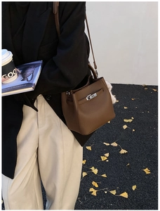 Brown litchi grain leather mini bucket bag with silver clasp styled for city commute