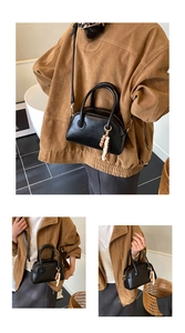 Détail d'un sac bowling vintage en cuir noir avec pompon en perles et logo gravé