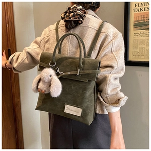 Detail of dark green suede backpack with silver logo plaque and plush rabbit charm