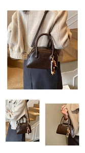 Gros plan du sac Boston vintage marron avec breloque perlée et bandoulière chic