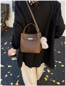 Detail of a brown lychee pattern bucket bag with silver lock and plush rabbit charm