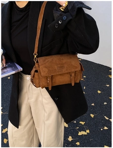 Brown suede crossbody bag detail showing classic buckle decor and flap texture on a model