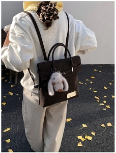 Detail of dark brown faux suede backpack with plush rabbit charm on a street with leaves