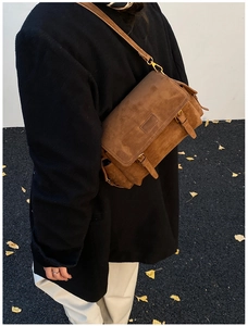 Close-up of vintage brown suede crossbody bag with metal buckle and slim shoulder strap