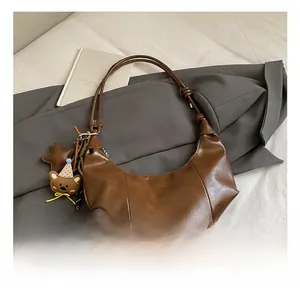 Detail einer braunen Hobo-Tasche mit Anhänger und niedlichem Bären-Charm