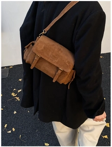 Brown faux suede crossbody bag with vintage double buckles shown on a model