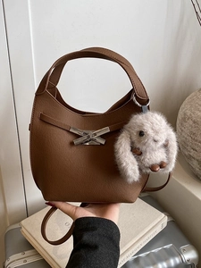 Brown lychee grain leather bucket bag with metal bow clasp and plush rabbit charm