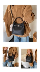 Close-up of black litchi leather bucket bag with silver clasp and grey fur ball charm
