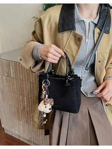 Matte black bucket bag with plush charm on a model wearing an autumn outfit