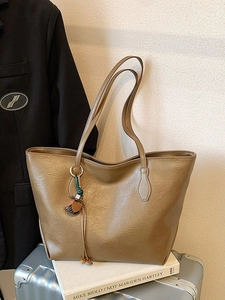 Minimalist beige tote bag with floral tassel on a suitcase for commuting and travel