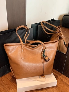Chic tan faux leather tote bag with elegant rose charm for stylish daily commuting