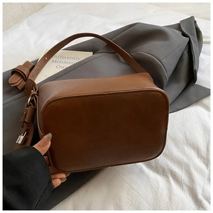 Detail view of the vintage brown leather texture and adjustable metal buckle on shoulder bag