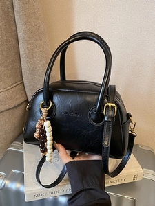 Retro black leather bowling bag with top handles and a decorative beaded charm
