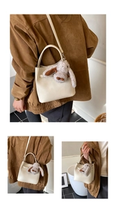 Close-up of beige lychee grain leather bucket bag with a cute grey plush bunny pendant