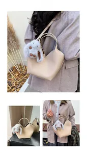Détail du sac seau beige en cuir grainé avec un charmant pendentif lapin en peluche