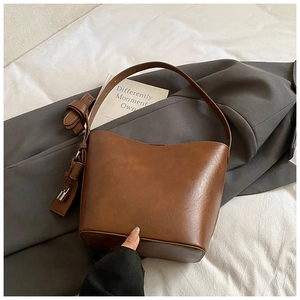 Detailed close-up of brown vintage leather bucket bag with silver metal buckles and straps