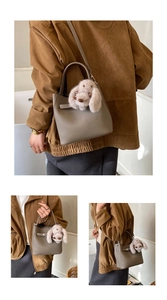 Grey pebbled leather bucket bag with plush rabbit charm shown in multiple angles