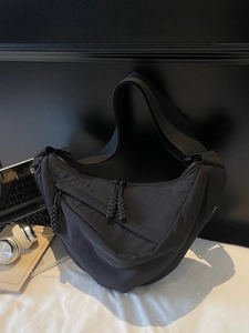 Black nylon crescent crossbody bag with woven zipper and adjustable shoulder strap