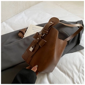 Brown litchi grain bucket bag detail with leather bow and silver metal padlock charm