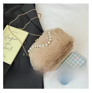 Détail du sac beige en peluche avec poignée en perles et chaîne dorée sur blazer