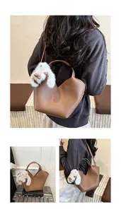 Détail du sac seau vintage marron à motif litchi avec breloque lapin en peluche blanche