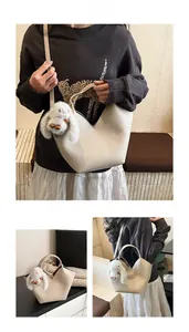 Détail du sac seau en cuir grainé avec ouverture en V et breloque lapin blanc