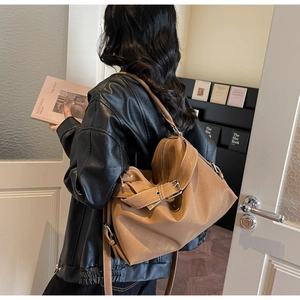 Detail view of large brown matte leather tote bag with adjustable straps and metal buckles