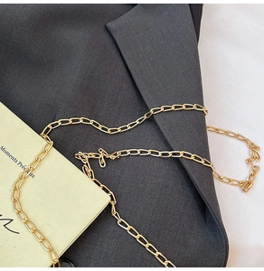 Détail d'une bandoulière chaîne dorée élégante sur tissu texturé avec carte