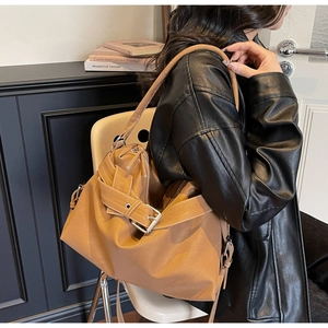 Detail view of large camel tote bag with buckle decor and matte leather texture