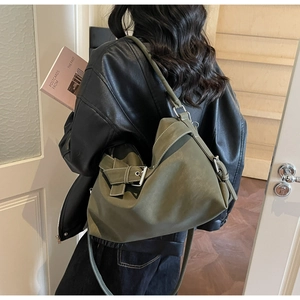 Detail showing the olive green tote bag with contrast stitching and silver metal buckle