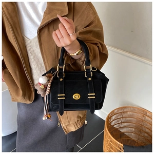 Detailed shot of black matte leather handbag with gold twist lock and pony charm accessory