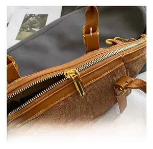 Detail shot of golden metal zipper and buckle on a brown textured crossbody handbag
